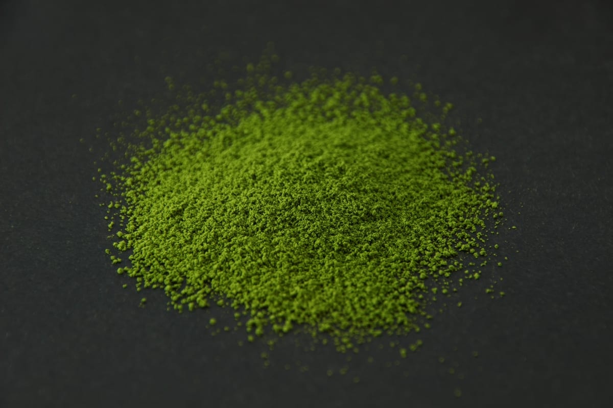 Bright green YMSC matcha powder heaped on a dark surface