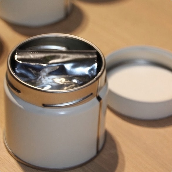 A sealed sachet placed inside an open tin