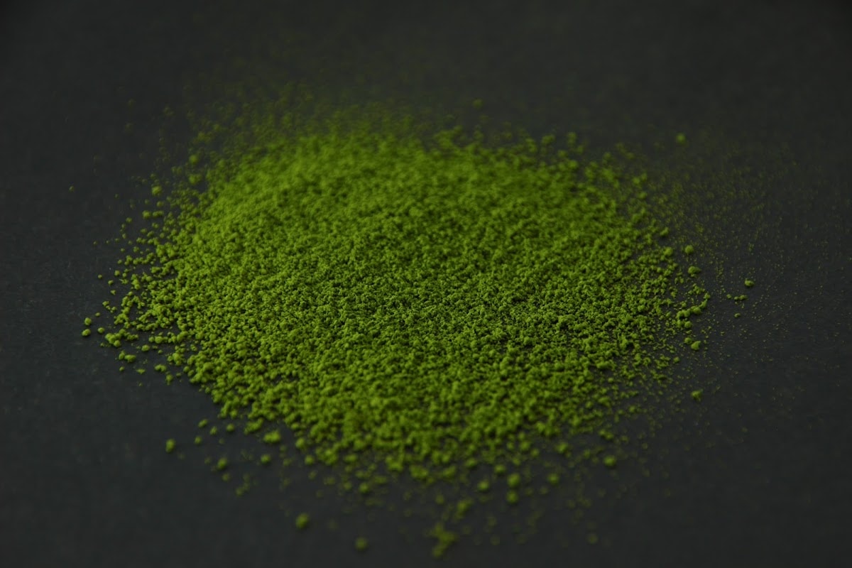 Bright green SR8 matcha powder heaped on a dark surface