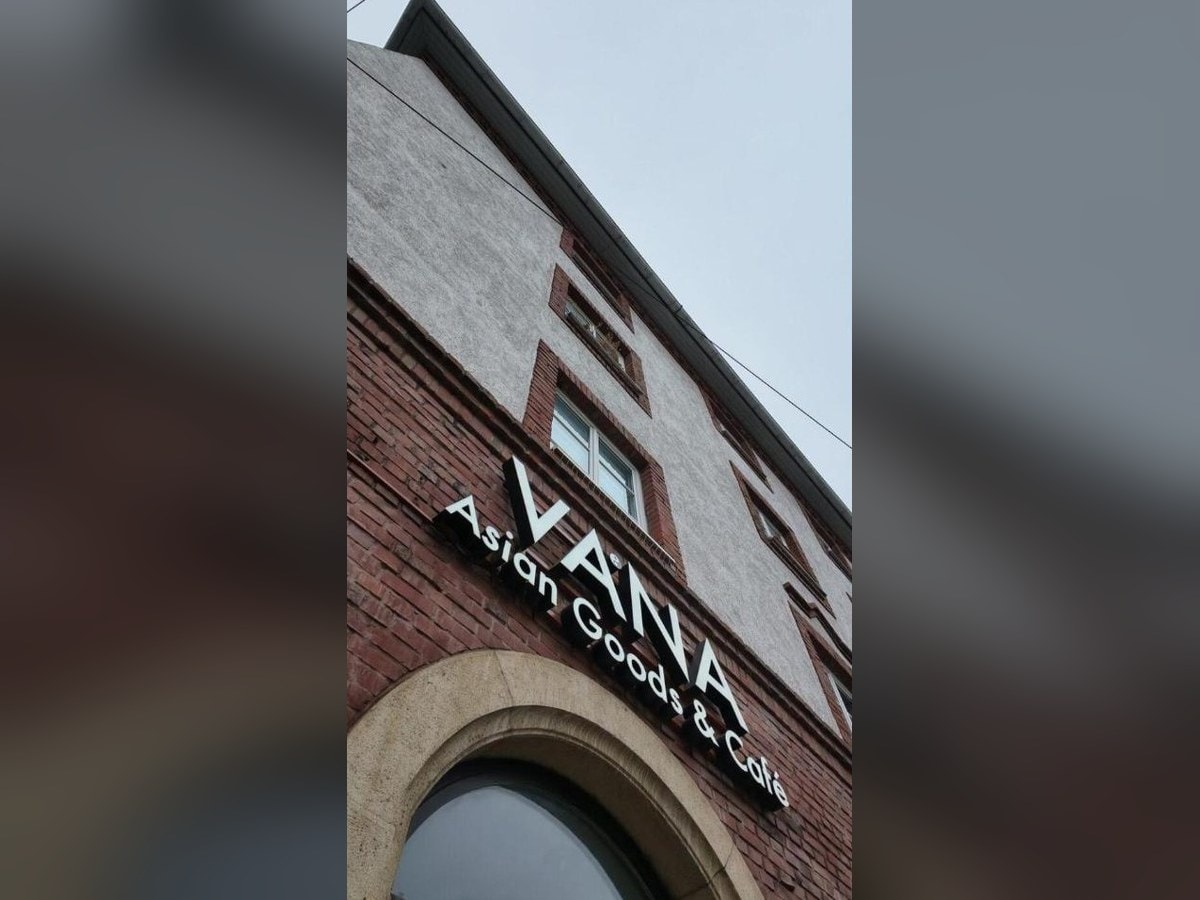 VANA Asian Goods & Café sign on a red-brick building in Munich, an Asian grocery with a matcha café attached